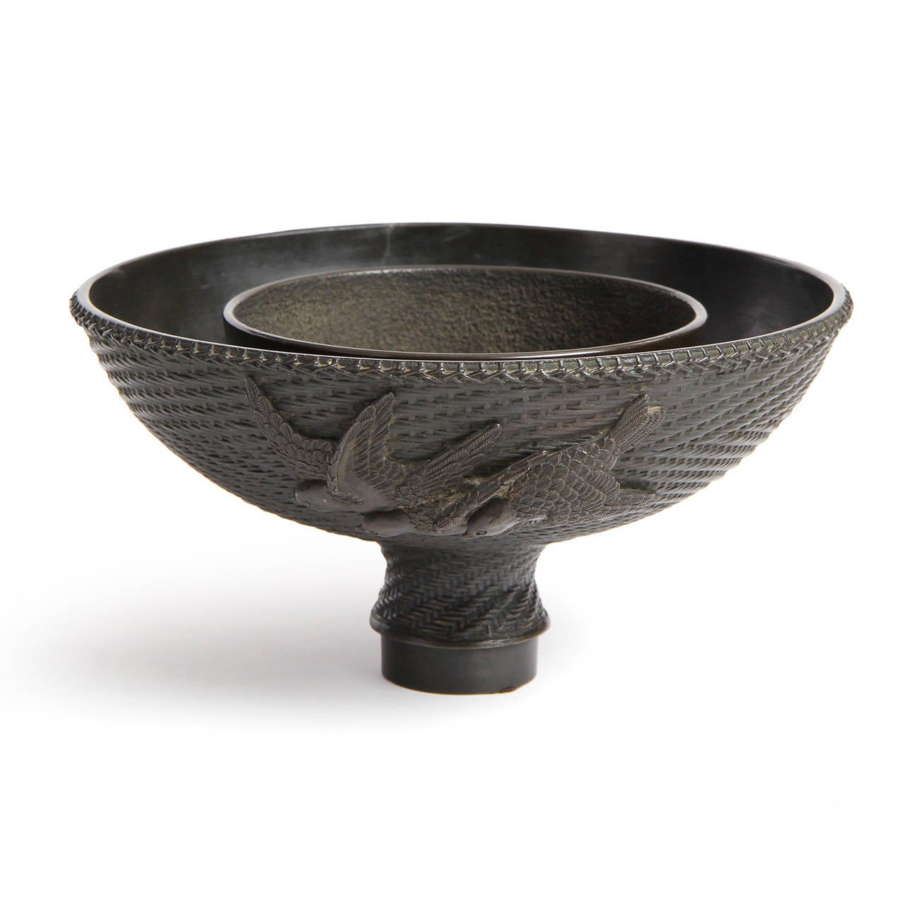 A blackened bronze Ikebana bowl from the Meiji period, in the form of a herringbone-weave basket raised on a small foot, with bas-relief birds in flight.