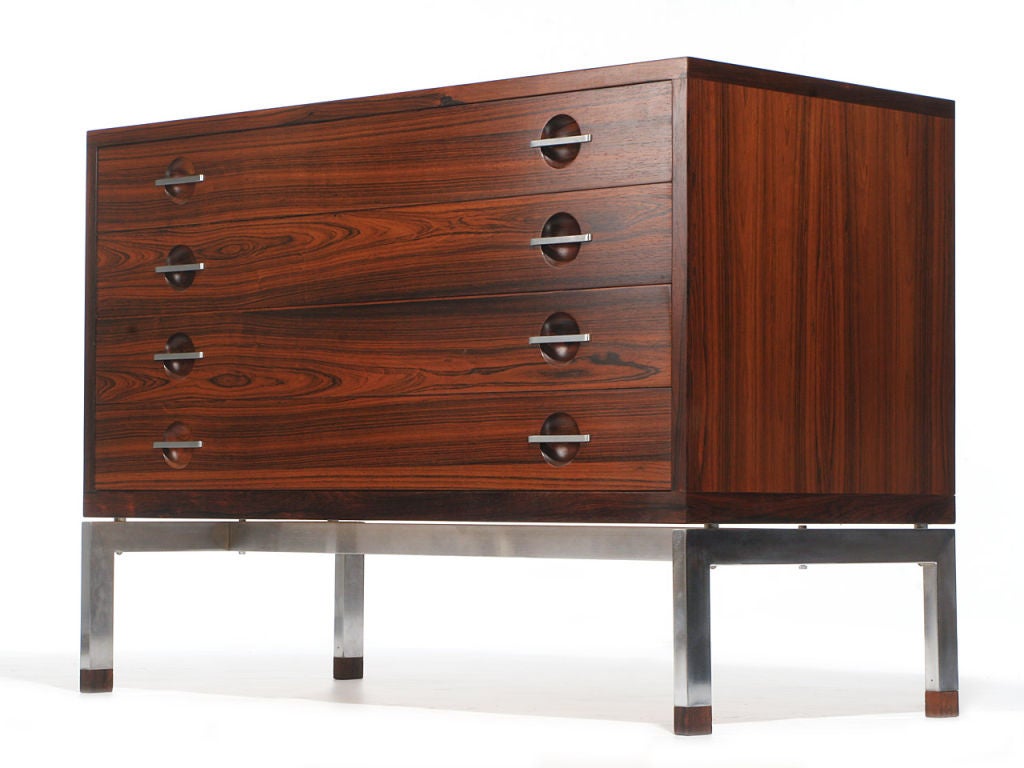 A rosewood four drawer cabinet on satin chrome legs with rosewood feet.