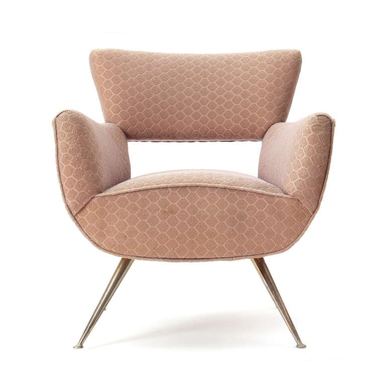 A dynamic armchair by the Italian designer Gaston Rinaldi having a sculpted, upholstered seat over splayed and footed brass legs.