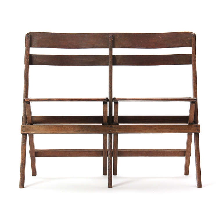 A finely crafted and uncommon American folding two-seat bench in stained oak, having contoured seats and back rests.