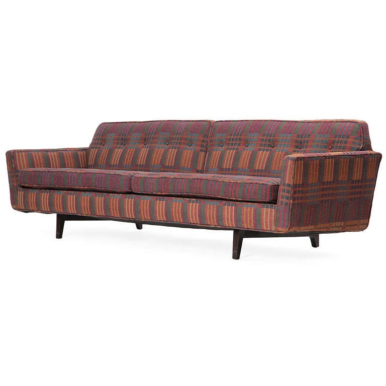 A fine and uncommon sofa of generous scale and long and low proportion, that floats on a dramatic carved walnut frame with sculpted back legs and retains its period patterned upholstery.