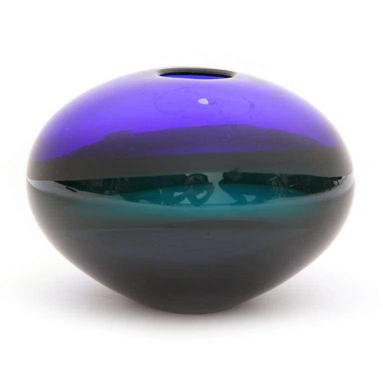 A gorgeous and expressive sculpture in blown glass having a spherical form and expressively blended planes of color that transition from black-to-blue-to-purple-to green.