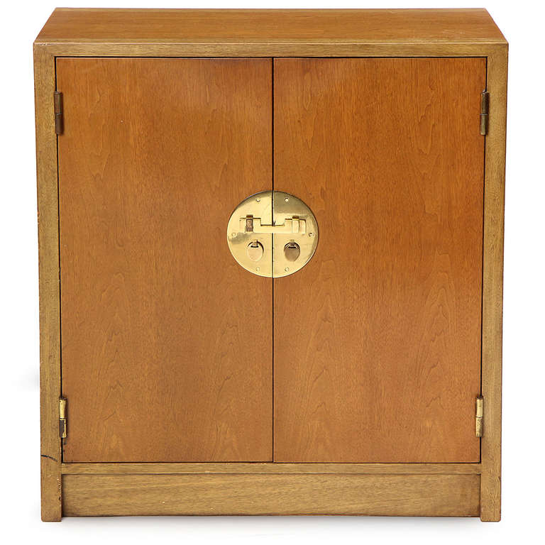 An elegant rectilinear light walnut two-door cabinet having Chinese-influenced hardware and a rare configuration of twelve cushioned flat drawers.