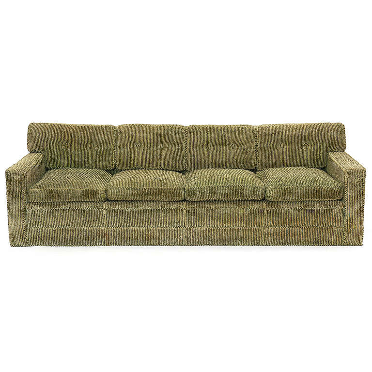 A stately and beautifully proportioned sofa, having a tufted and sectioned back with wide and comfortable flattened arms. The cushions are down filled and the fully upholstered sofa retains its original rich open-weave sage green-chestnut wool