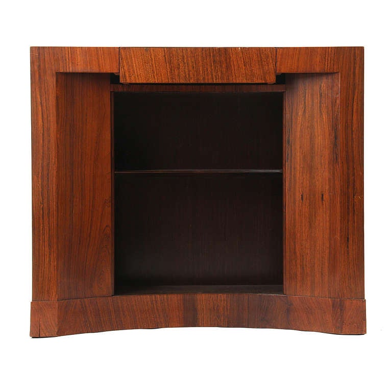 A rare curved front console in rich grained rosewood with a single drawer and slatted tambour storage.