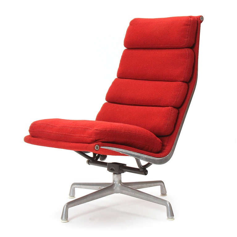 An armless soft pad swivelling lounge chair in original red wool channeled upholstery by Charles Eames for Herman Miller.