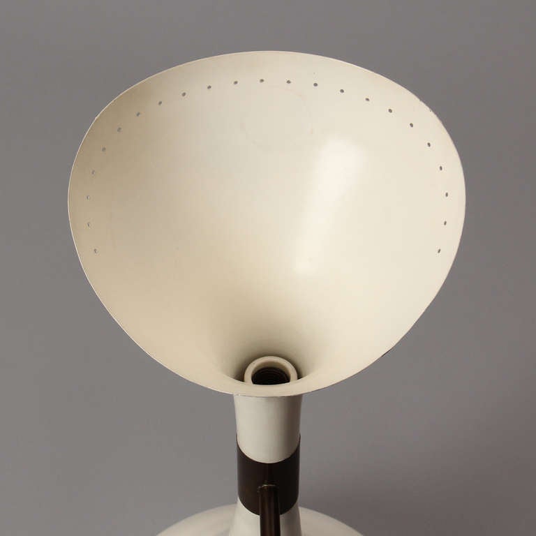 A brass and white enameled metal wall lamp with a single uplight and two adjustable direction flood lamps.