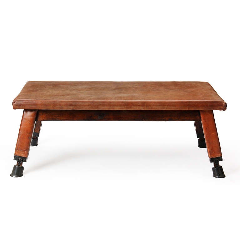 Banc de gymnastique recouvert de cuir, reposant sur des pieds en pin ébonisé, évasés et recouverts de cuir, et sur des pieds en fonte patinée.