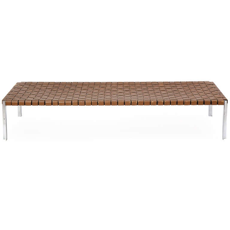 A bench or daybed of great scale and proportion having an architectural machined steel frame wrapped with woven straps of thick aged saddle leather.