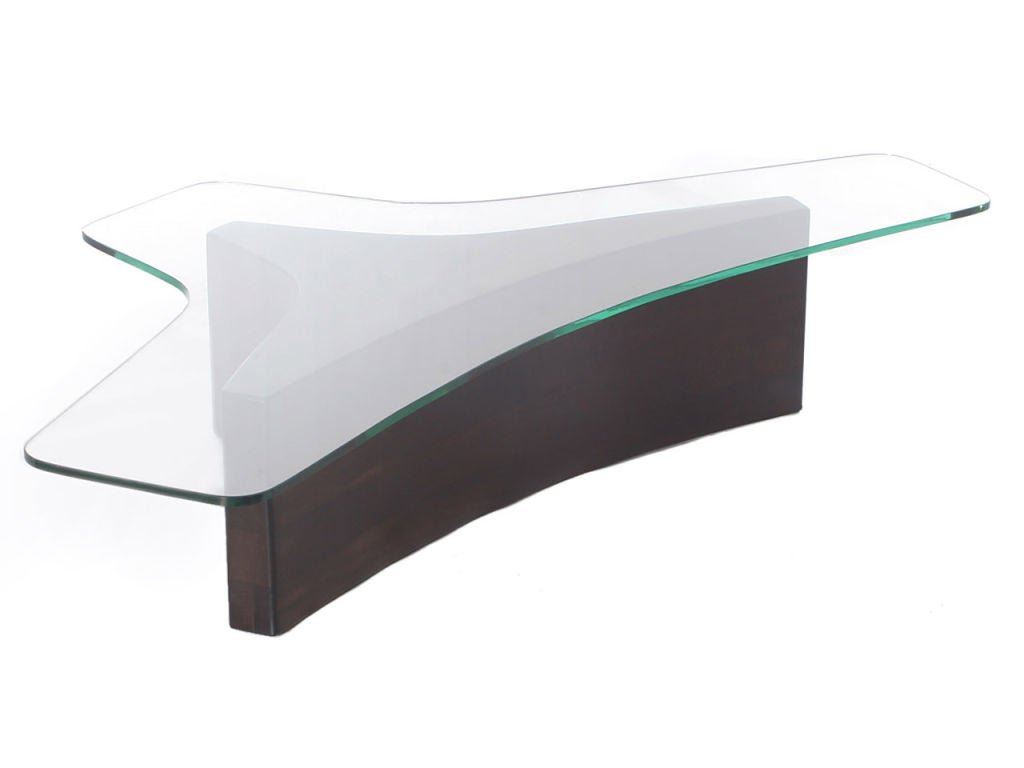 Ein niedriger Tisch mit einer Glasplatte und drei gelenkigen Beinen formt ein organisches Design.