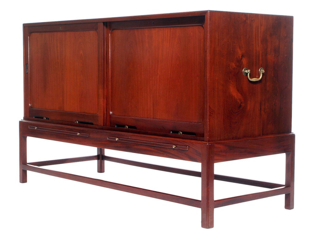 A stately and beautifully crafted two-piece cabinet in rich solid Cuban mahogany having sliding doors with recessed oval pulls. Interior shelves slide out and are re-configurable. The base and cabinet are two separate pieces, the base having two