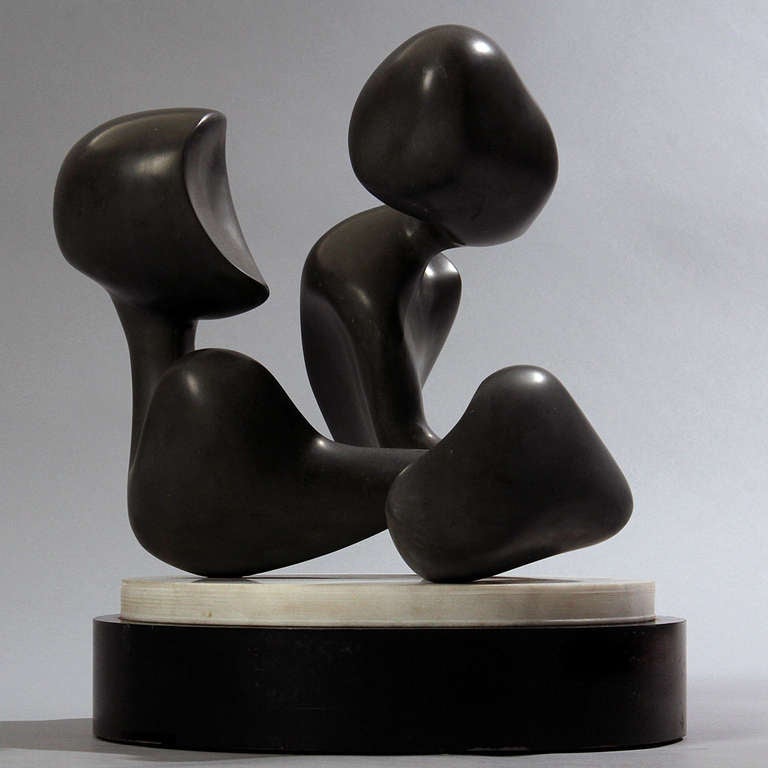 A finely rendered abstract biomorphic sculpture in polished black stone mounted onto a marble rotating base.
