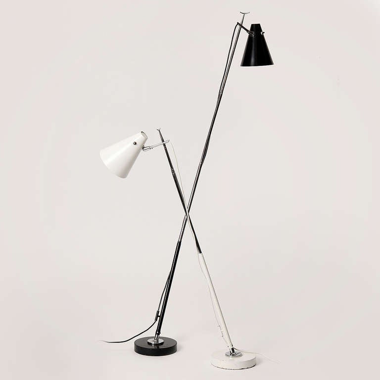 Innovative and highly adjustable telescoping floor/desk lamps with pivoting cone shades on enameled and chromed steel stems with  ball-and-socket jointed weighted disc bases.