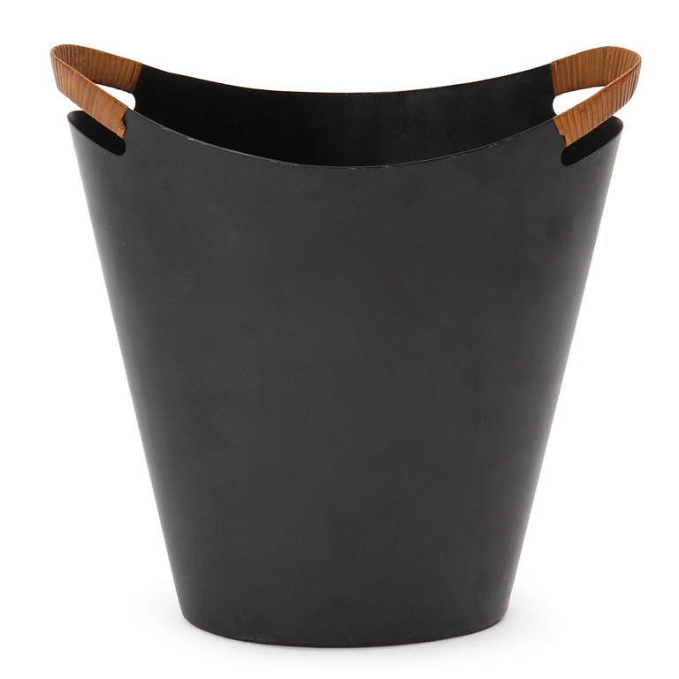 An excellent waste basket having a sleek, sculptural profile crafted in thin-gauge steel with distinctive cane-wrapped handles.