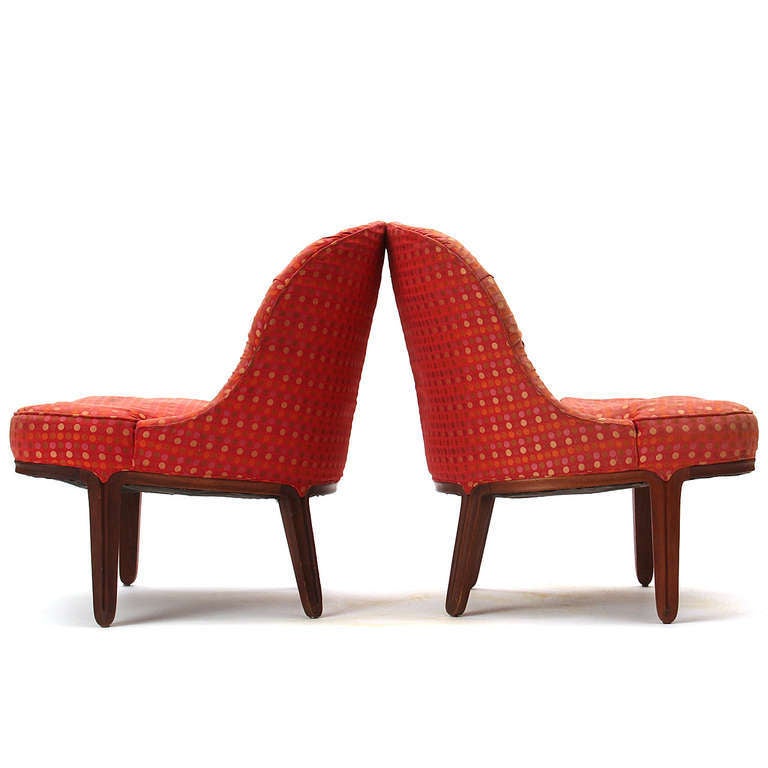 A pair of curvaceous and generously scaled tufted slipper chairs on mahogany legs.