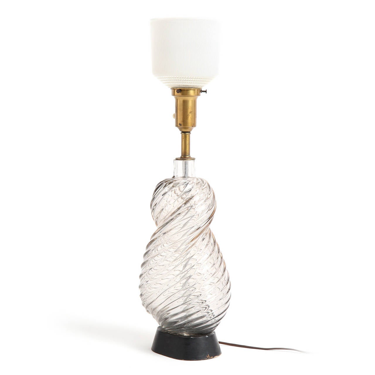A table lamp with an organic spiraling and striated form crafted of thick clear glass and resting on a lacquered wooden base.