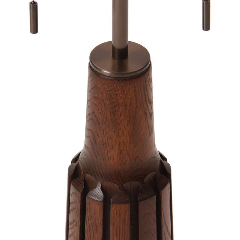 A tapering table lamp carved from a single blank of Burmese teak, having two sockets and encircled by parallel cut channels. Base height is 14.5