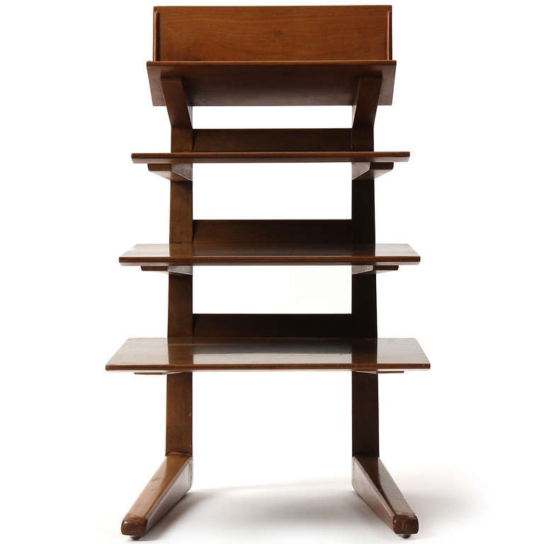 An uncommon and beautifully executed stand in walnut having four (4) cantilevered shelves of descending scale hanging over an elongated angled base.