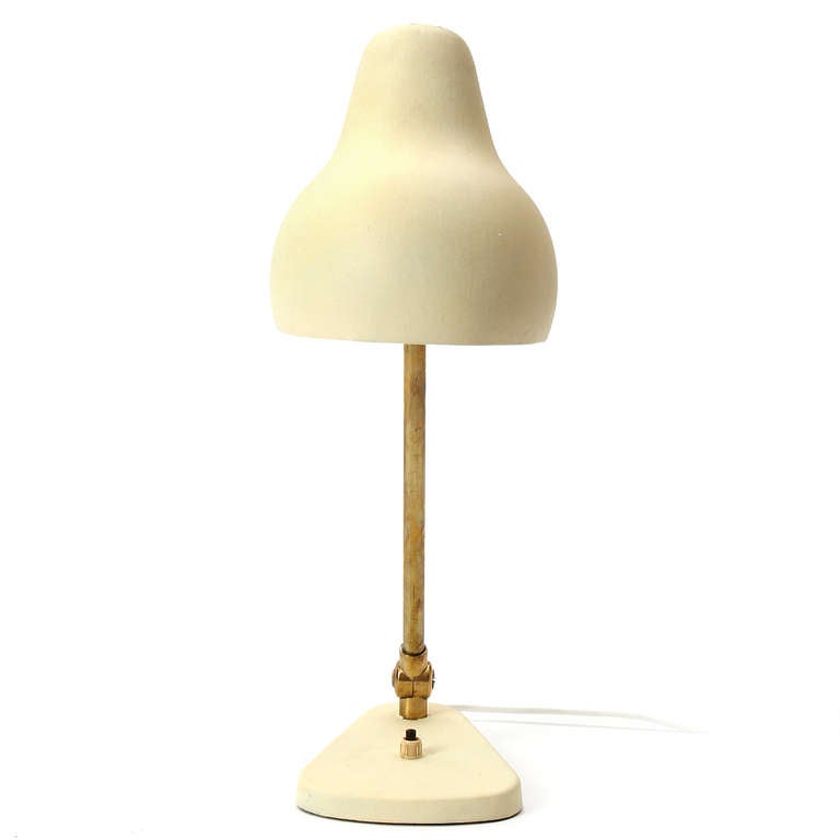 A articulating desk lamp having a brass stem and a cream enameled base and hood.