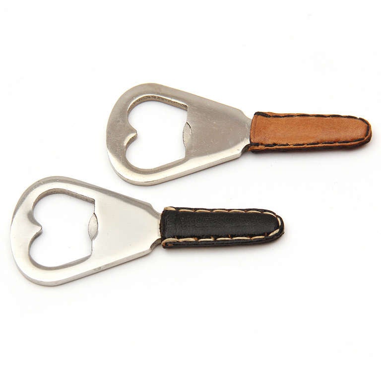 A petite paddle shaped stainless steel bottle opener with hand-stitched leather handle.