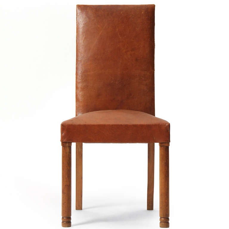 Un ensemble de quatre (4) chaises de salle à manger à haut dossier avec des pieds avant tournés en chêne, et des pieds arrière effilés conservant le revêtement d'origine en cuir naturel.
