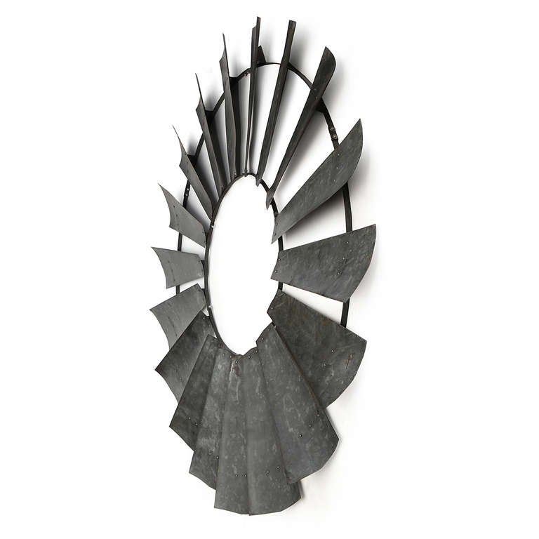 Ein großer und schön patinierter Satz von Windturbinenflügeln aus verzinktem Stahl, die in einem radialen Muster angeordnet und durch zwei Stahlringe verbunden sind.