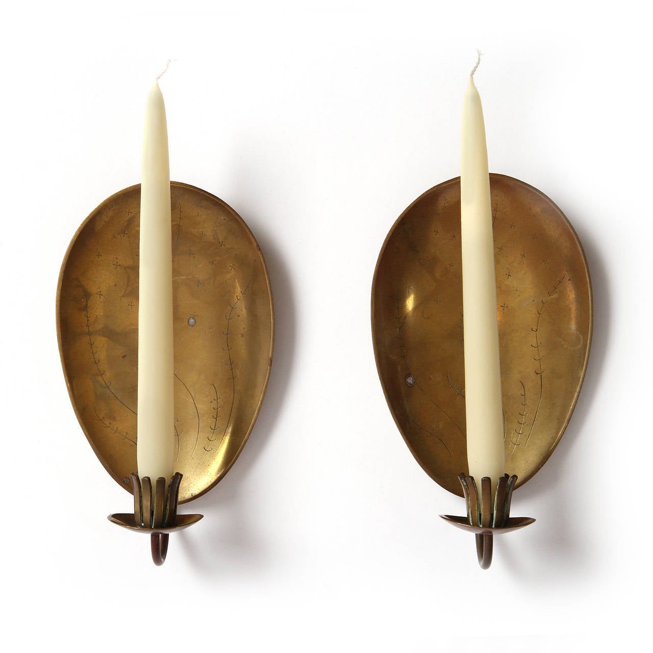 A beautiful pair of hand crafted patinated bronze candle sconces having flora engraved oval shields and organic slotted petal form candle holders.
