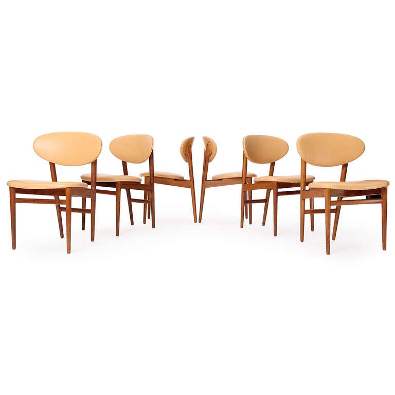A set of six unique dining chair of smaller scale having a teak frame and curved seat and back both upholstered in leather.