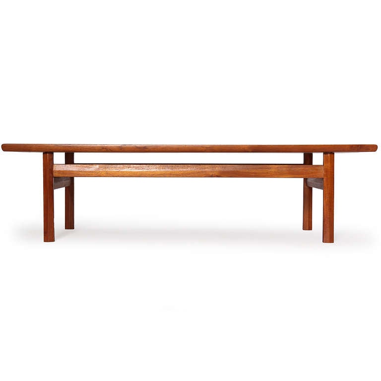 A Scandinavian low table designed by Ejner Larsen and Aksel Bender Madsen featuring a rectilinear form with chamfered legs and stretchers supporting a teak top with raised edges. Made in Denmark, circa 1950s.