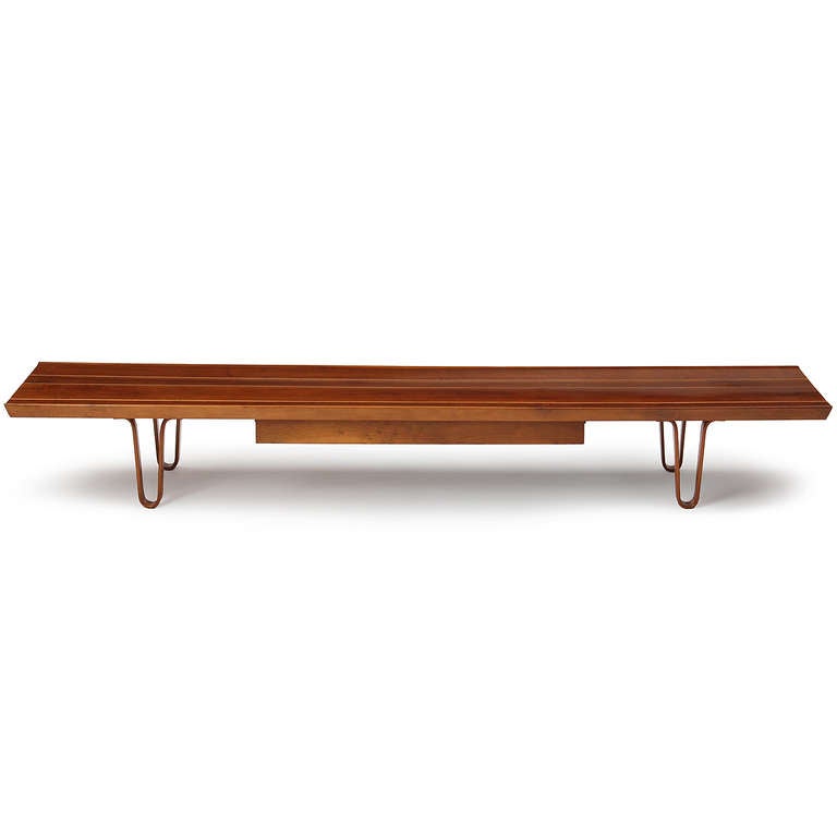 An elegant and masterfully simple low table or bench by Edward Wormley having a top of joined and grooved slats of walnut on bentwood hairpin legs and a single floating drawer.
