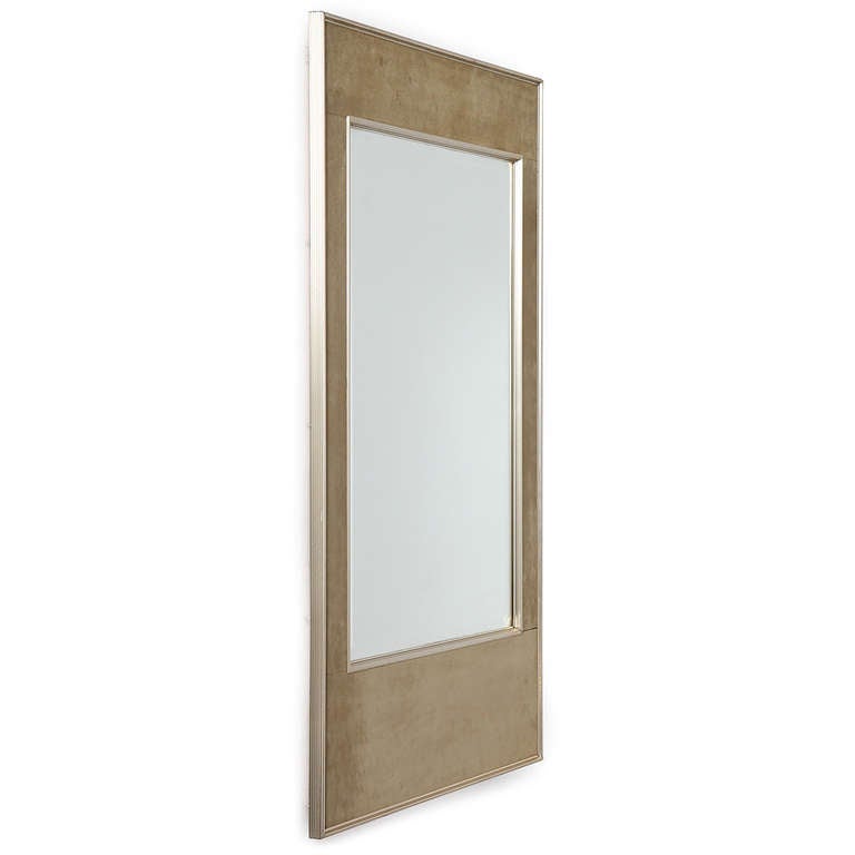 An elegantly double framed mirror with khaki suede paneling between the interior and exterior frame.