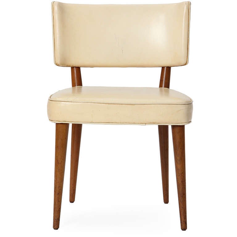 An elegant game or dining chair with a curved back and generous seat atop tapered dowel legs, with rear legs that continue up to support the back.