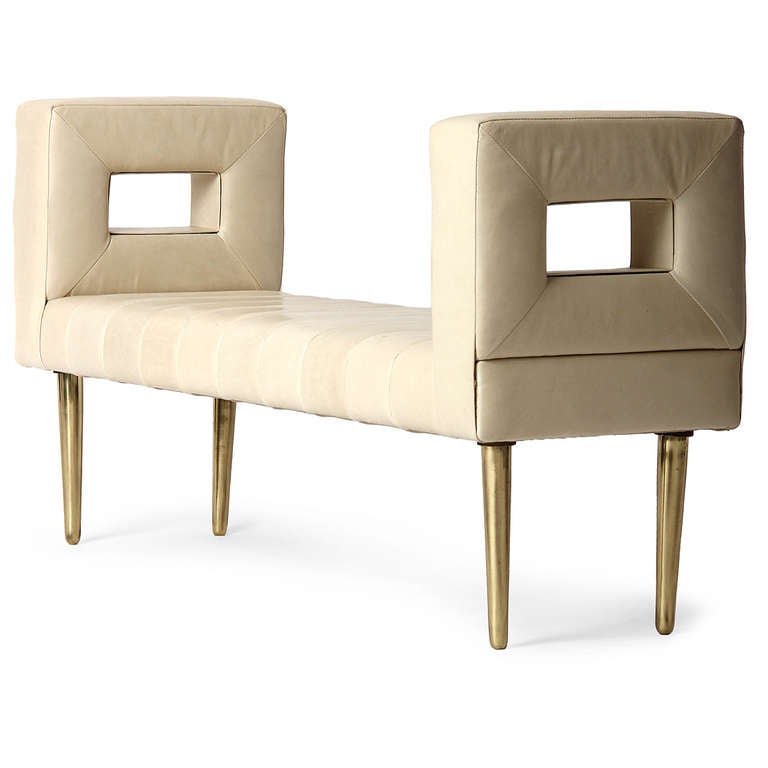 An elegant and sculptural bench or settee having channeled white leather upholstery and squared open ends perched on turned brass dowel legs. By Edward Wormley for Dunbar.