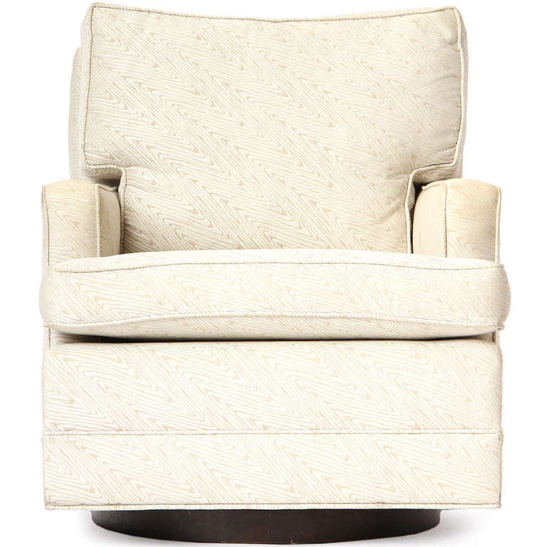 Ein schöner und bequemer Dreh- und Kippsessel, dessen Sitze auf einem minimalistischen, runden Nussbaumsockel ruhen.