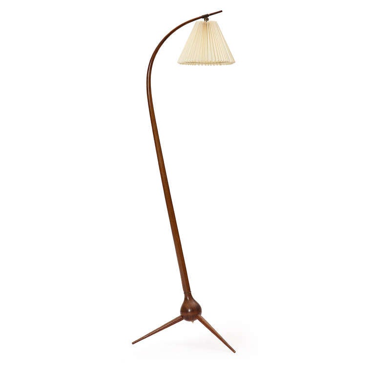 A unique and slender floor lamp in stained beech with a tripod base and a pleated shade.