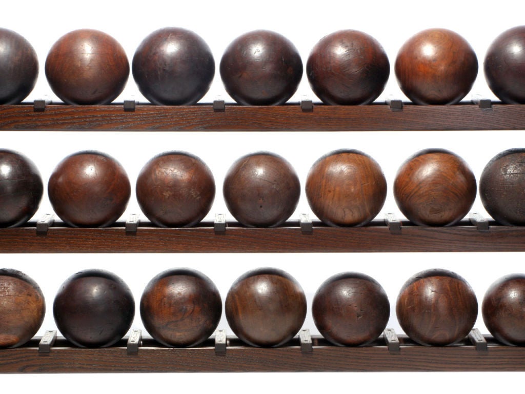 A custom made five shelf walnut bowling ball rack consisting of forty-five (45) regulation sized antique lignum vitae (heartwood) lathe turned bowling balls.