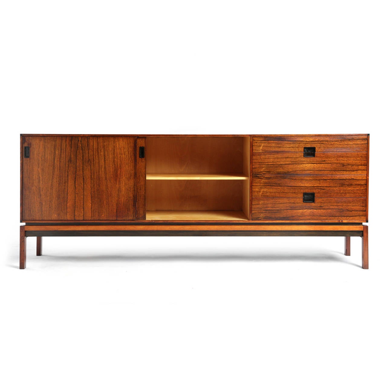 A refined and elegant sideboard crafted of richly grained rosewood with ebonized edges and recessed pulls. Having sliding panels and drawers, one drawer designed to hold flatware, cabinet floats on a raised architectural base.