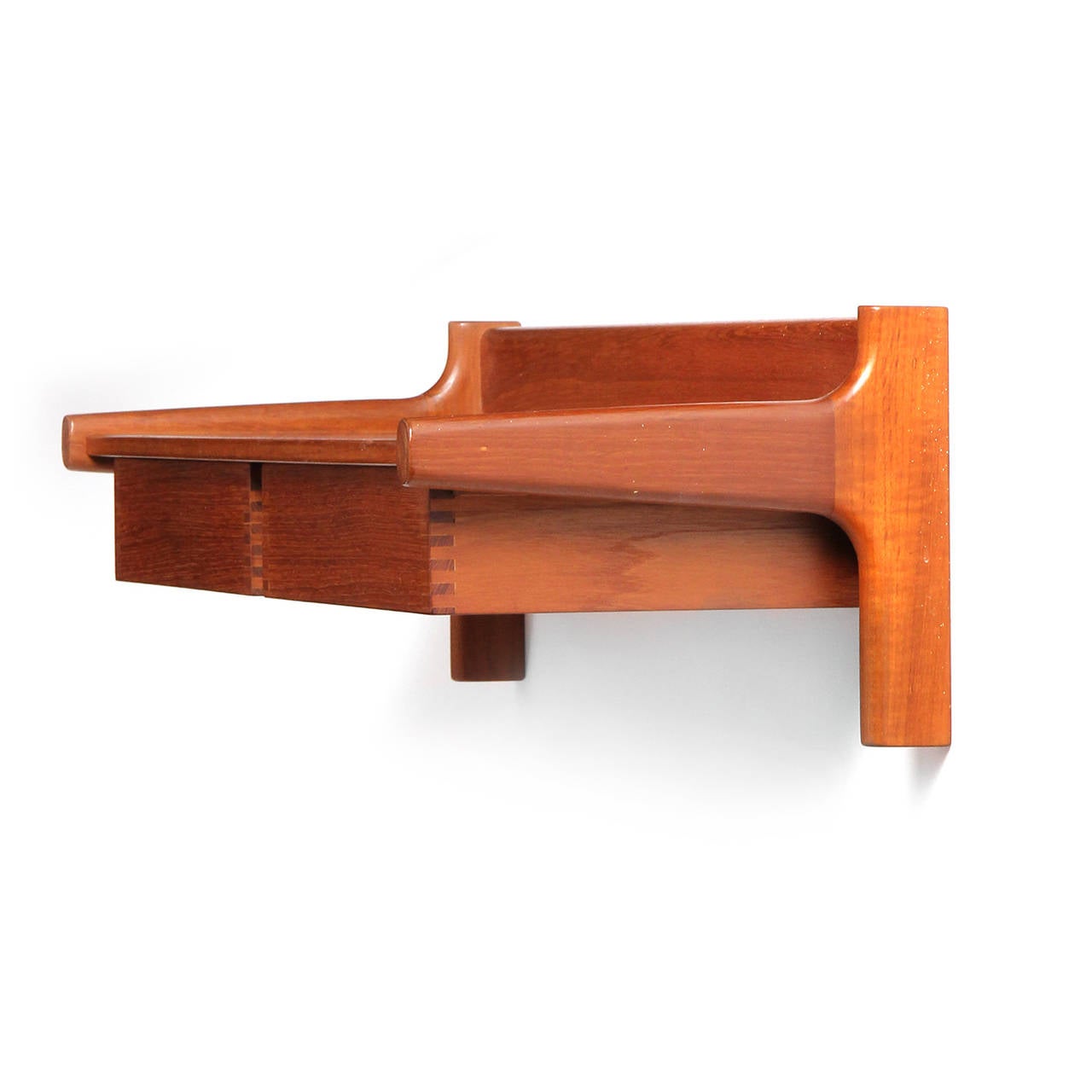 A teak wall mount shelf with two floating, finger-jointed drawers.