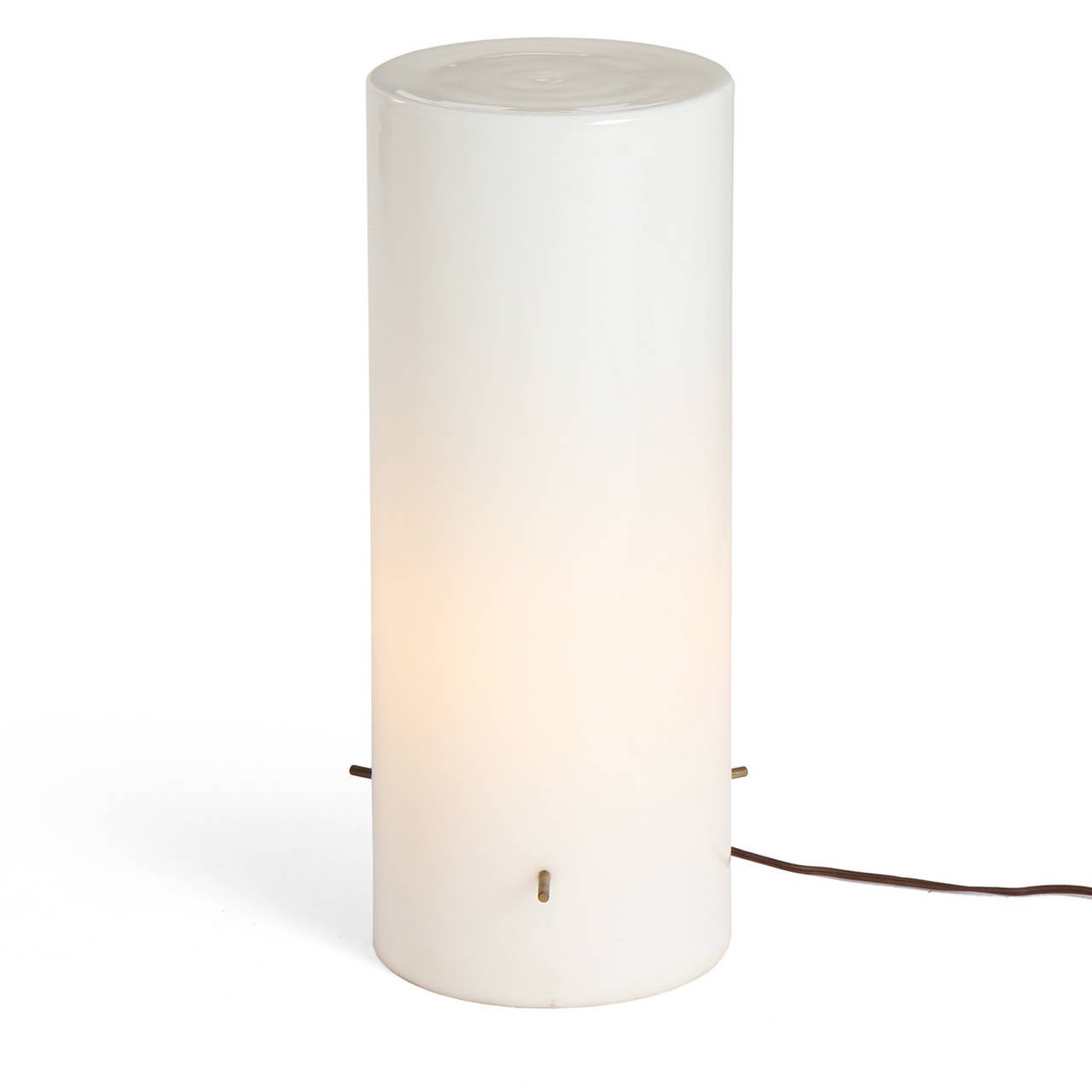 A spare and elegant table light composed of a well executed tall white cased glass column with a floating light source held in place by three patinated brass threaded pins.