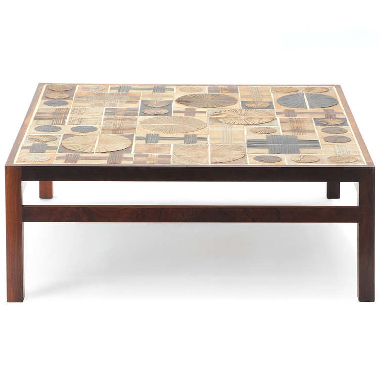 A square low/occasional/coffee table of warmth and depth by the Danish ceramicist Tue Poulsen having a rosewood bordered top of inset hand crafted earth-toned tiles in linear and rounded patterns.