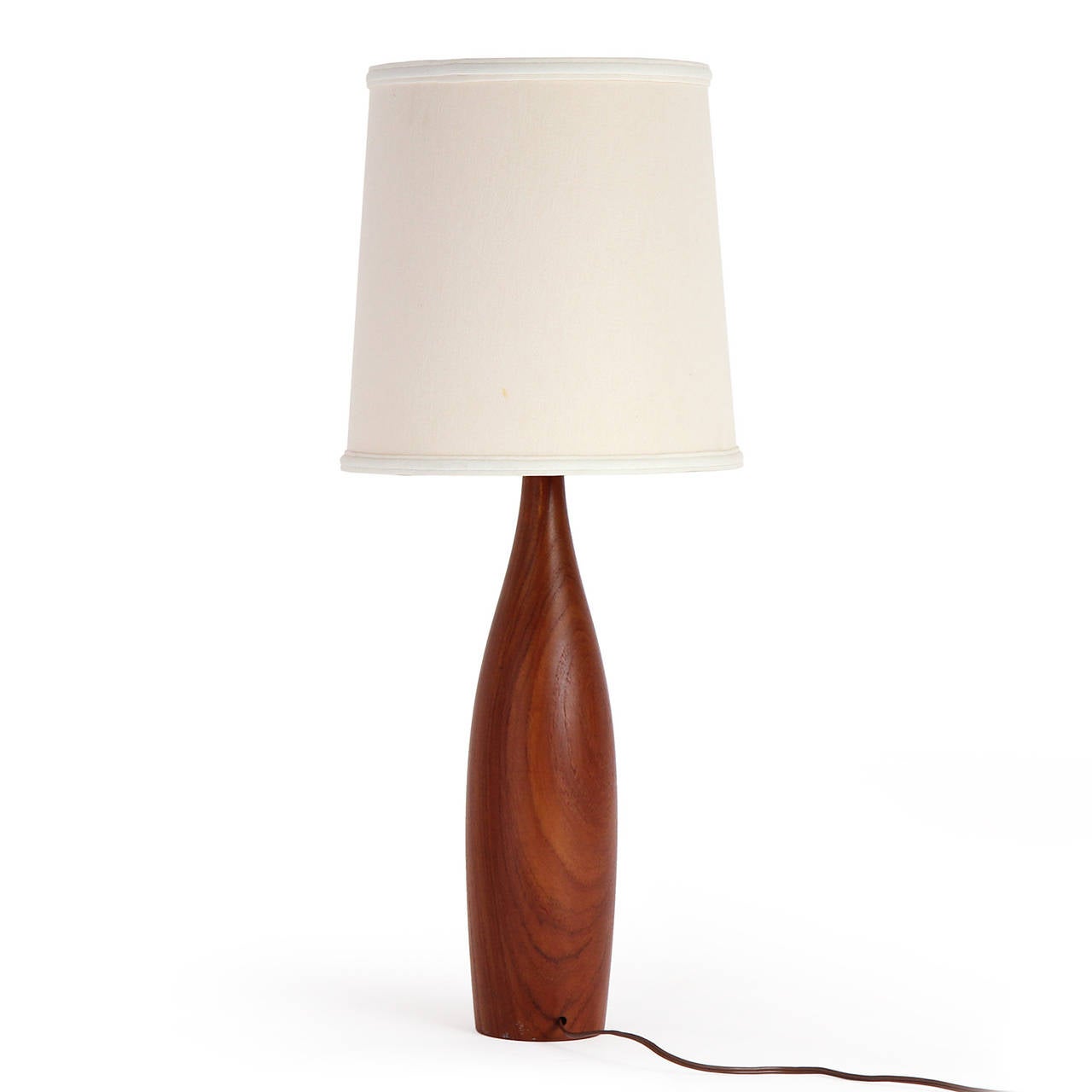 A finely turned, substantial and elegant pair of table lamps turned from a single piece of warmly toned and vividly grained teak.