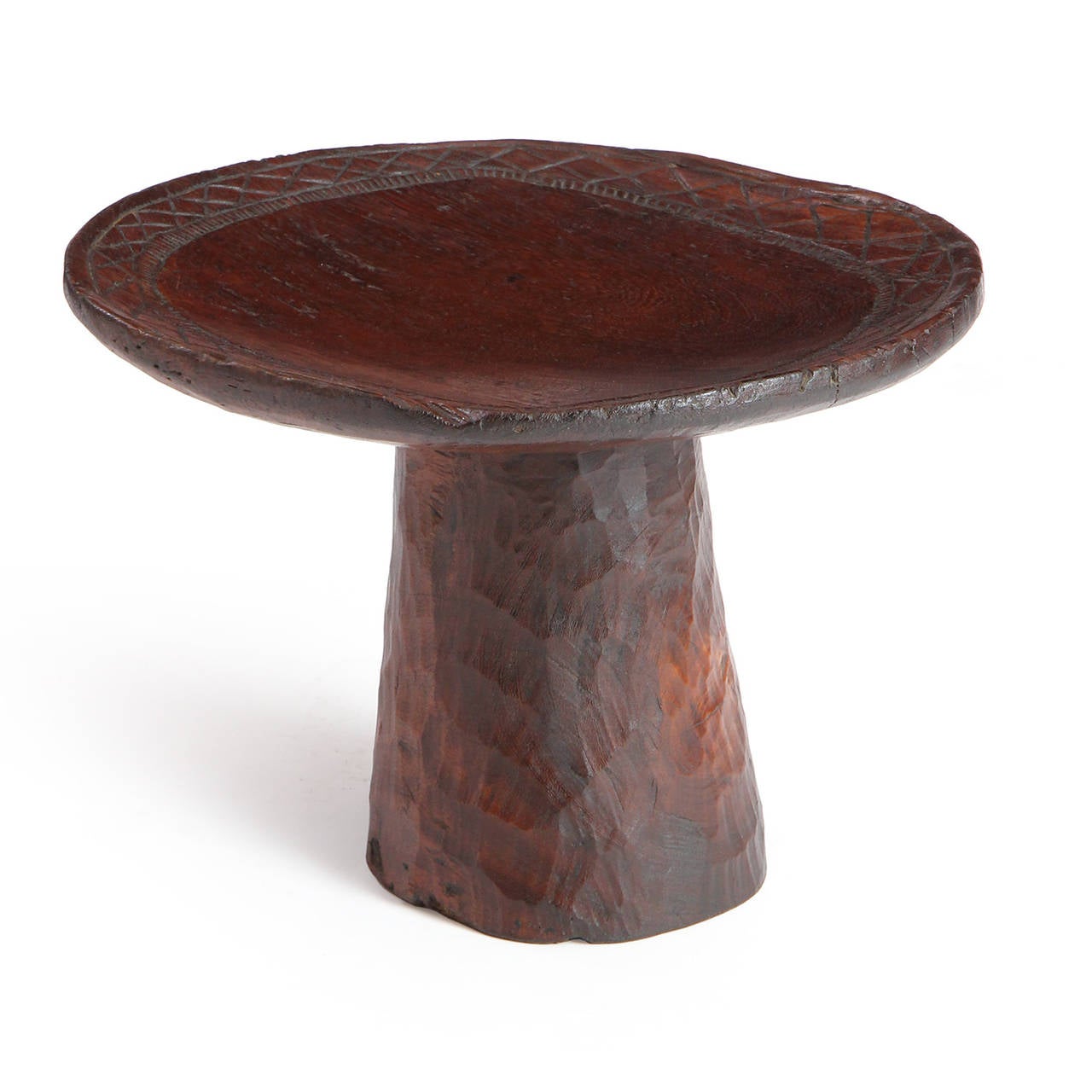 A magnificent, soulful and uncommon diminutive table or pedestal carved from a single block of richly toned African hardwood and having incised cris-cross patterning around the perimeter.