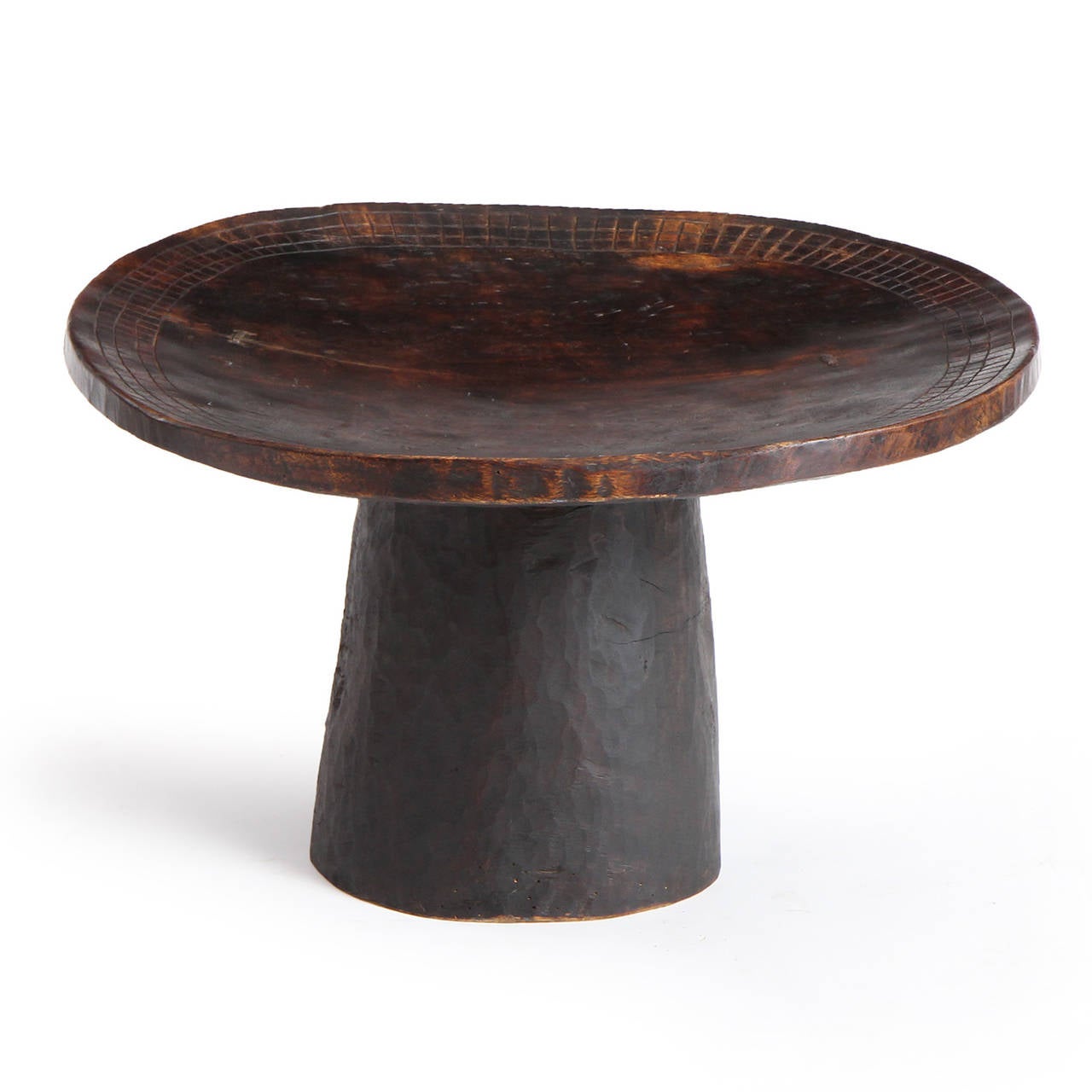 A magnificent, soulful and uncommon table or pedestal masterfully carved from a single block of richly toned African hardwood and having incised patterning around the perimeter.