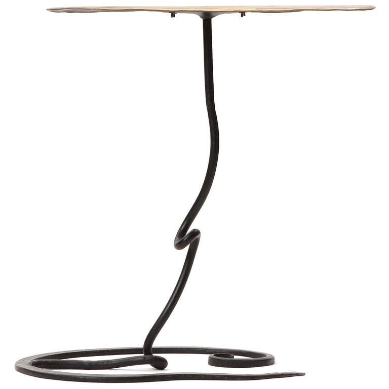 A handcrafted, sculptural side table having a patinated biomorphic bronze top floating atop an undulating wrought iron base.