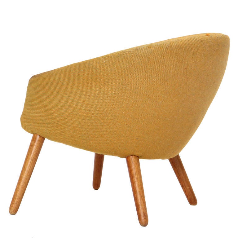 A barrel-back upholstered lounge chair on four tapered splayed dowel legs.