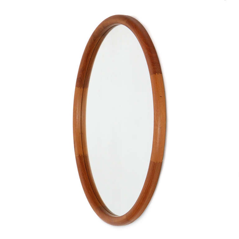An exceptionally simple round teak wall mirror with a bull nose shaped frame.