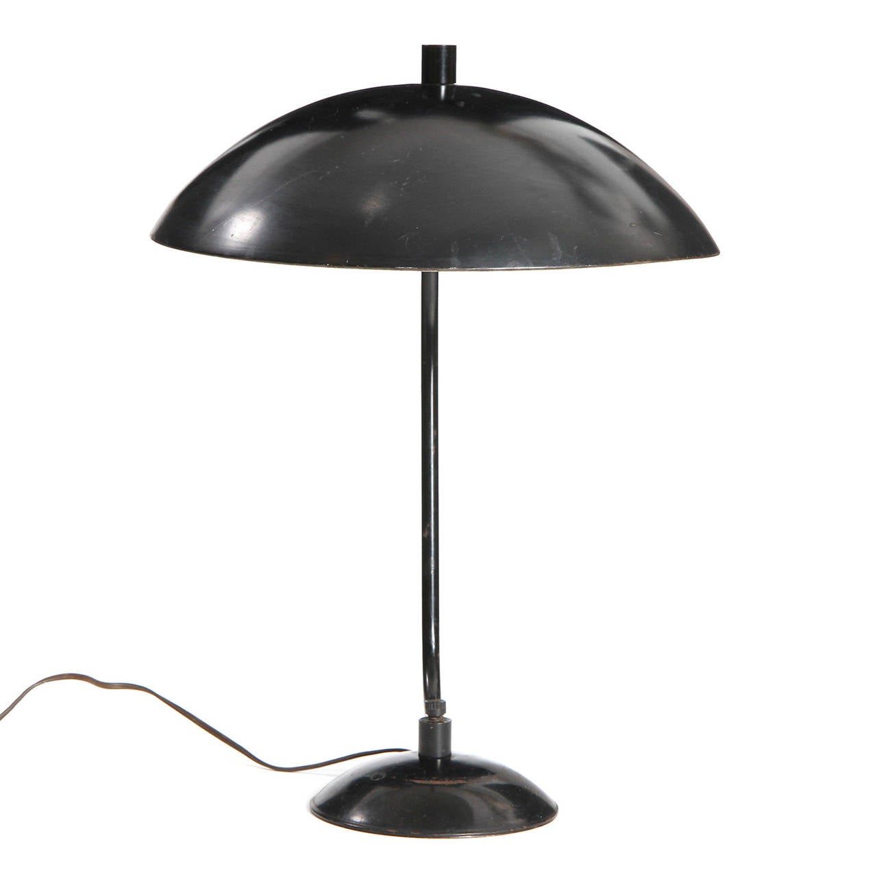 A modernist table lamp having a hemispheric shade suspended from a spare and sculptural tubular steel arm that rises from a weighted disc base.