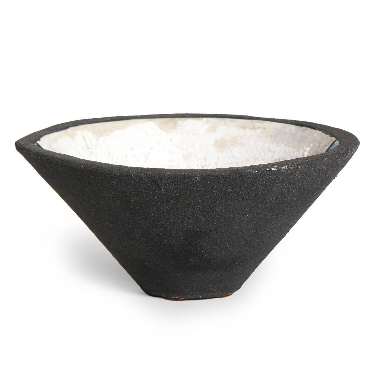 A unique and unusual hand built ceramic bowl having a steeply tapered oval form and covered with a matte black volcanic outer glaze and graphic cobalt blue and white divided interior.