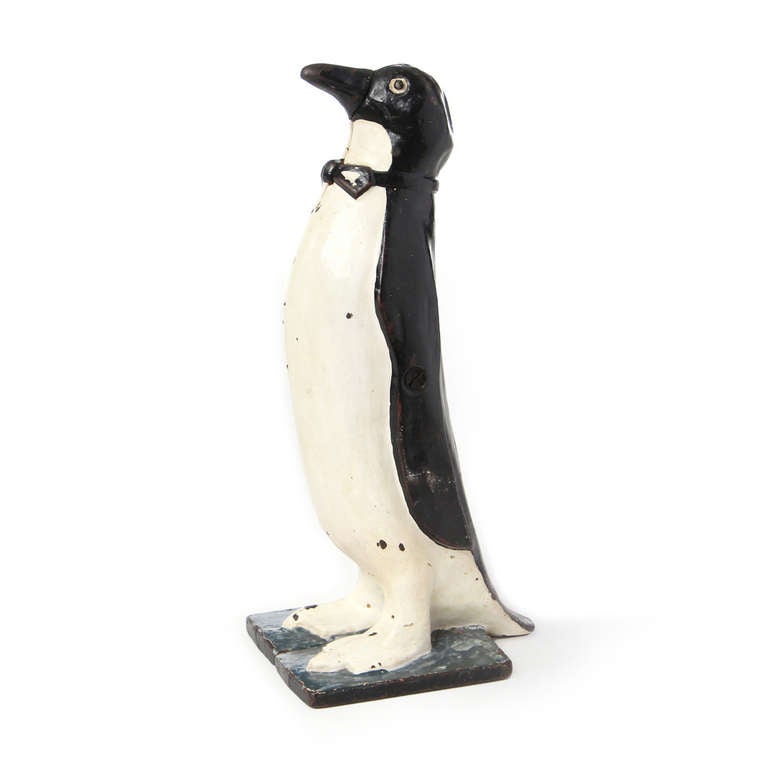 A whimsical penguin made of a two part iron casting and hand painted enamel to be used as a door stop.