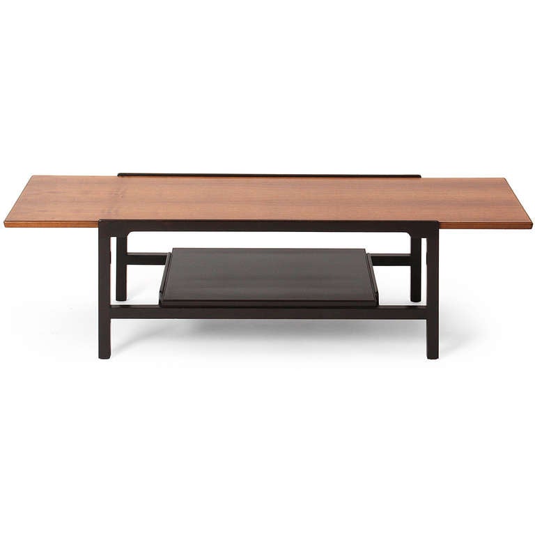 A low table or bench with an ebonized walnut frame which rises slightly above the table surface and can hold a loose cushion if used as a bench.